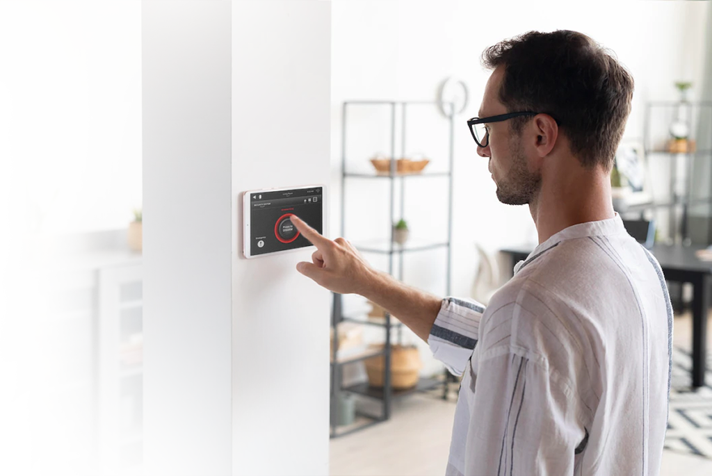 Homem controlando automação residencial através de tablet em cozinha moderna - Custom Theater